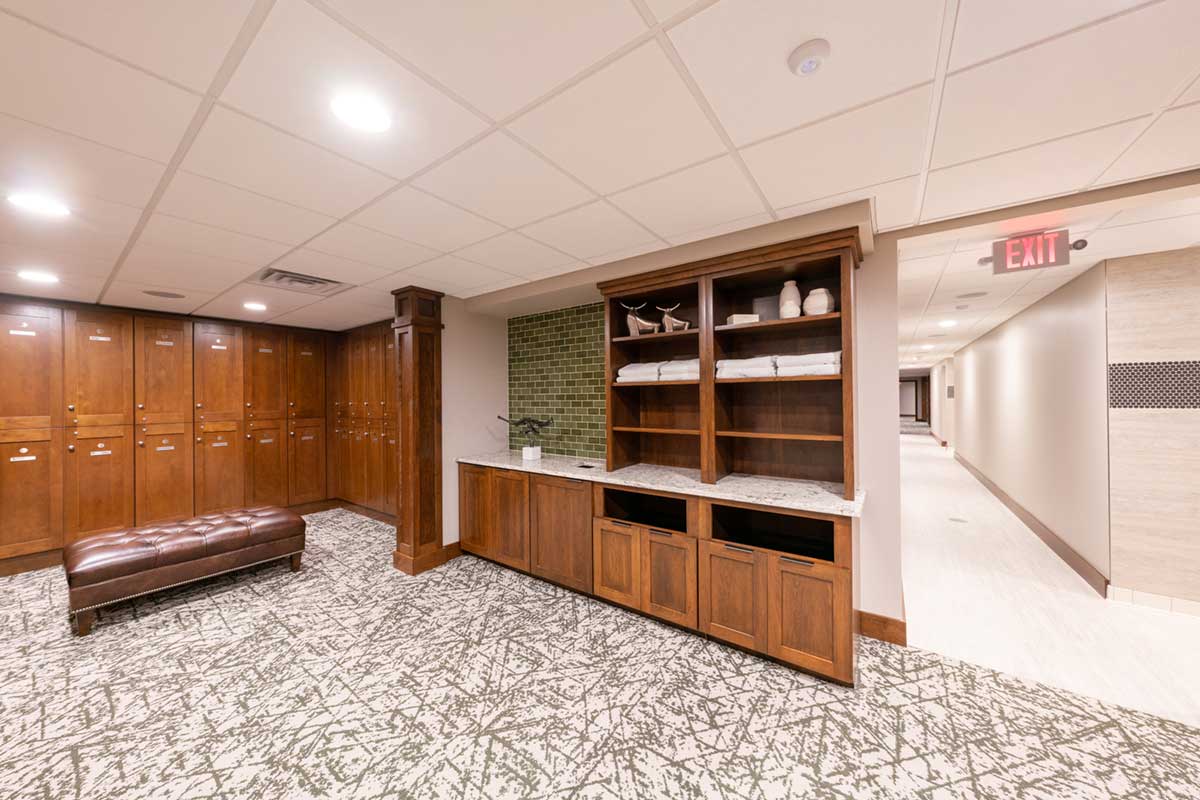 locker room with wood lockers and brown leather ottoman