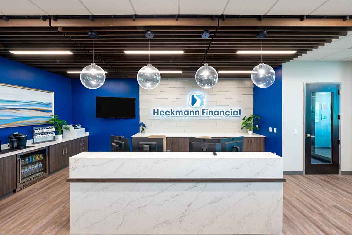 reception desk with Heckmann Financial sign behind, round globe lights, white marble counter, bright blue walls behind
