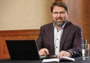 Jeff Grundahl sitting at table with open laptop and notebook