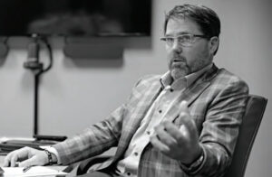 Black and white photo of Jeff Grundahl sitting at a table